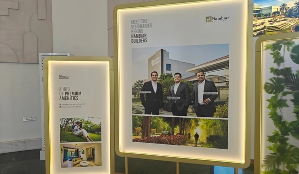 Illuminated display board at Nambiar District 25 sales gallery featuring the founders and visionaries behind Nambiar Builders