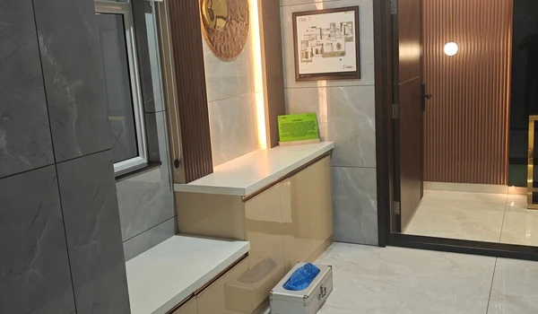 Entrance foyer of the 3 BHK model flat at Nambiar District 25, featuring a shoe rack, wall decor, and a shoe cover dispenser box for visitors