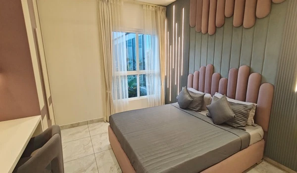 Modern kids or guest bedroom at Nambiar District 25 model flat featuring a unique pink and grey scalloped headboard, integrated vertical LED wall lighting, and large windows