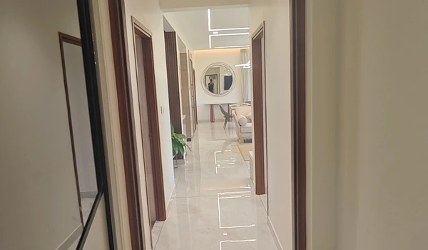 View from a private bedroom looking out into the polished marble hallway and dining area of the Nambiar District 25 4 BHK model flat