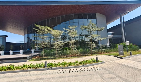 Close-up view of Nambiar District 25 marketing office featuring a curved roof design, large glass windows, and landscaped entrance