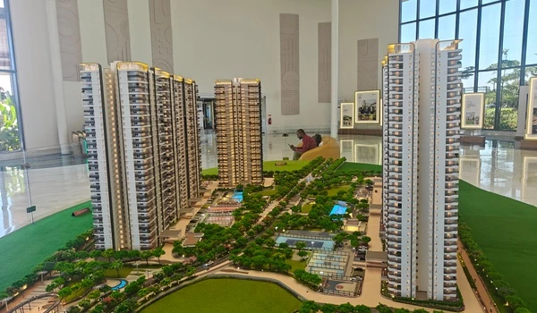 Aerial view of Nambiar District 25 model showing residential towers overlooking outdoor sports courts, swimming pools, and landscaped gardens